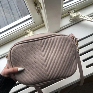 Väska - Hej! Jag säljer denna beiga/rosa väska från Åhléns, med en liten toffs på dragkedjan. Inga defekter men kommer tyvärr inte till användning. Hör av dig vid köp eller frågor🫶