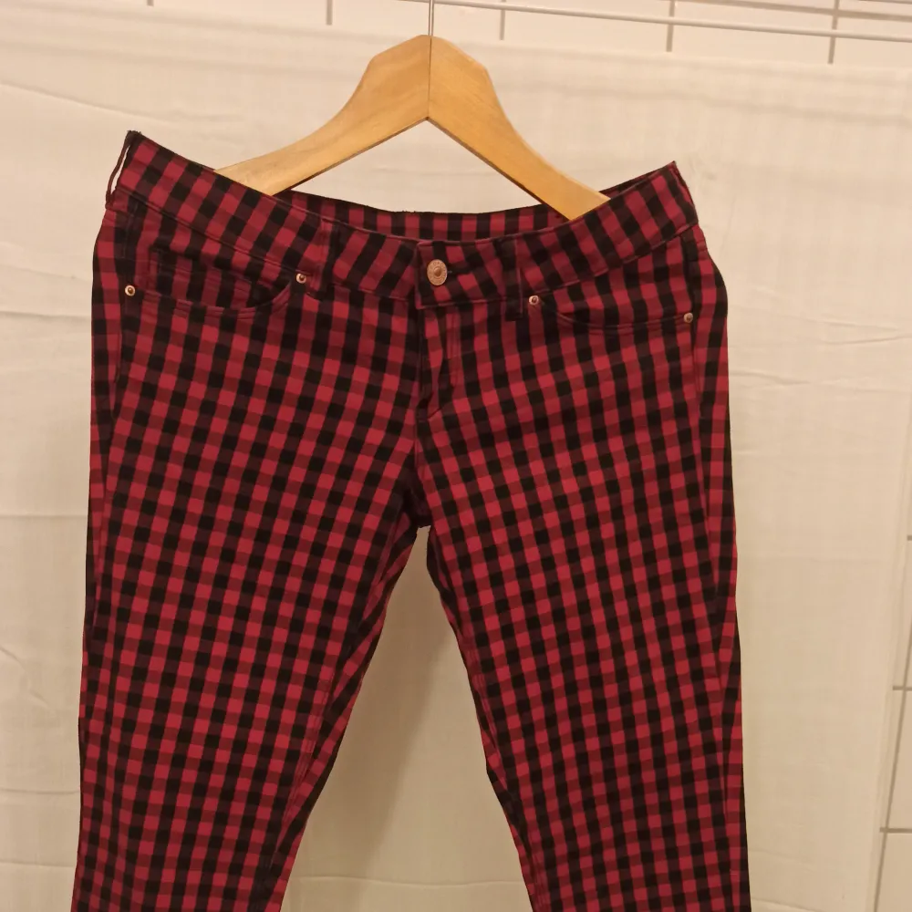 Fina rutiga röda och svarta byxor i bra skick. 98% Bomull, 2% Elastane. Längd från sida till sida i överkant 40cm.. Jeans & Byxor.