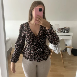 Omlott blus - En blommig omlott blus med pösiga armar den är V ringad. 