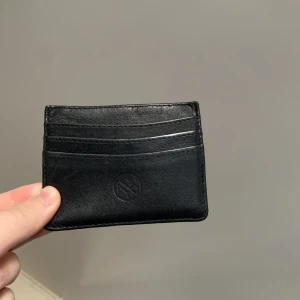 Korthållare - En svart stilren korthållare. Man får plats med 4 kort och har ett fack där man kan lägga t.ex. kvitton, sedlar eller mynt. Köpt för 150kr.