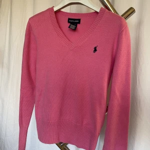 Stickad tröja Ralph Lauren storlek M (8-10) - Klassisk cerise v-ringad tröja från Ralph Lauren. Storlek M (8-10). Motsvarar cirka 128-134 cm. Fint skick. Djur och rökfritt hem. 