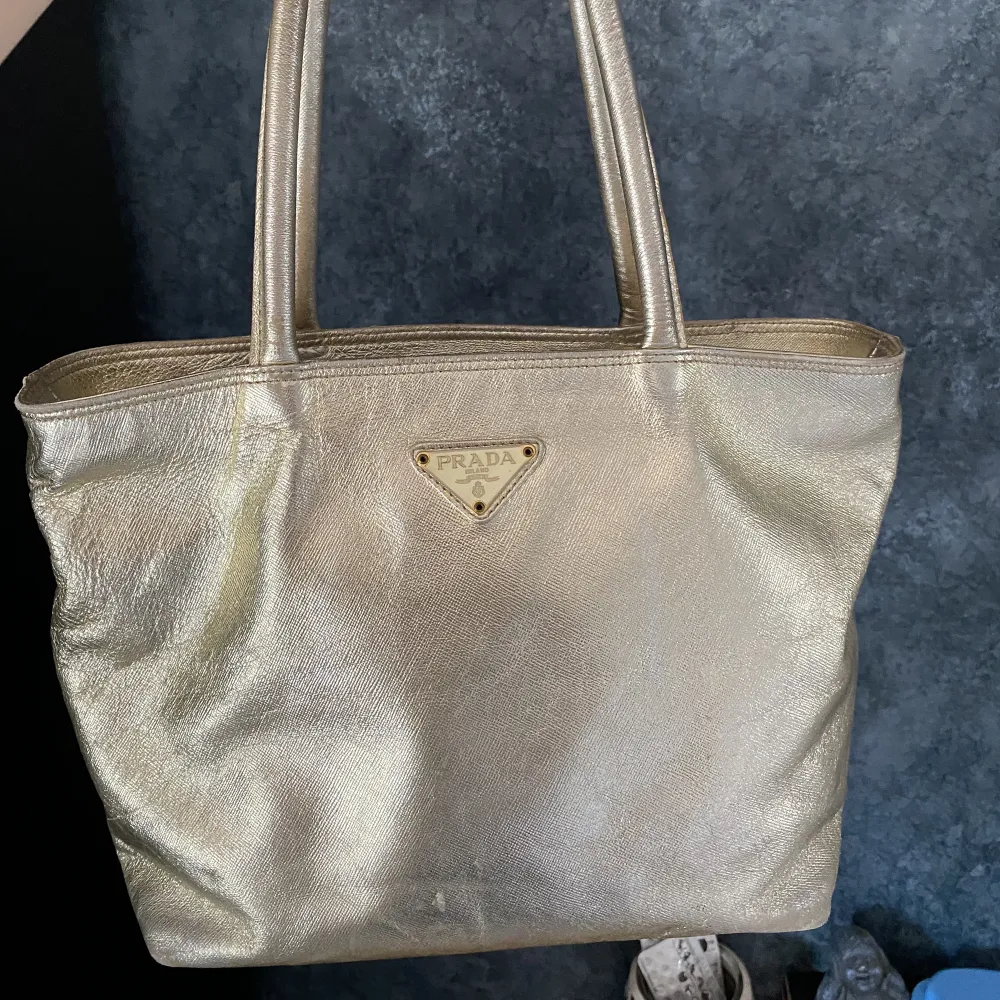 Guldig väska köpt second hand. Står att den är från Prada men skulle säga att det är fake . Väskor.