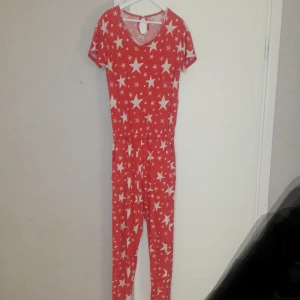 Röd One piece Chelsea pears strl M  - Superskön röd onepiece med vita stjärnor. Strl M. Perfekt att gå runt i under julen eller egentligen alltid när man är hemma haha. Fint skick förutom en söm som släppt lite vid kragen. Vet inte om. det syns på bilden men skriv så skickat jag bild i chatt 