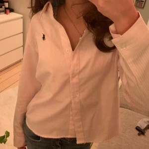 POLO RALPH LAUREN Rosa Skjorta - Såå snygg skjorta från Ralph Lauren, rosa-vit randig, i bomull. Nypris 1395 kr och jag säljer för 300 kr! 🩷🤍Saknas en knapp längst ner men ser snyggt ut ändå + nyskick annars!