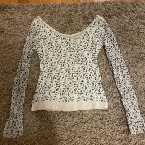 Mesh långärmad topp - Långärmad blommig topp i mesh material med fin urringning 