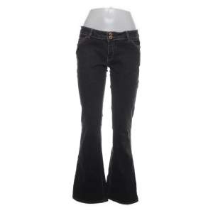 Gråa-svarta lågmidjade jeans med gulddetaljer på fickorna. Storlek S
