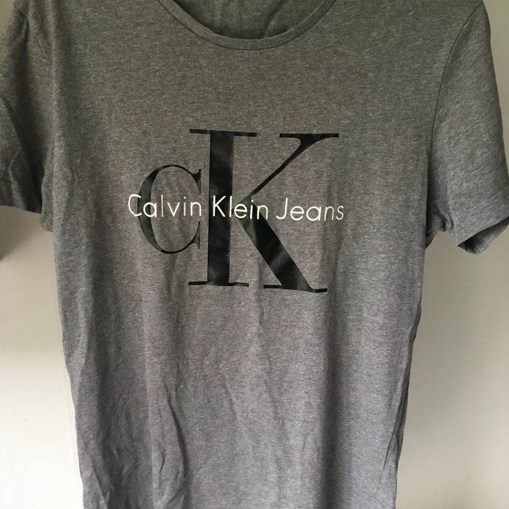 Grå Calvin Klein t-shirt. Liten spricka på en av bokstäverna (se bild).  I övrigt fint skick. . T-shirts.