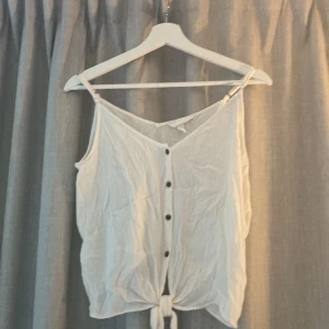 Vitt linne med knytdetalj - Lite skrynkligt men bra skick. Knappar framtill och knytdetalj längst ner. 