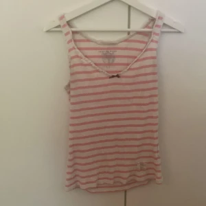 Odd Molly Linne - Rosa vitt linne med en röd rosett framtill. Väll använd men fin. Vit spets i kanterna. 