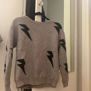 Tröja med blixtar  - Hej! Säljer denna fina stickade grå/ beige tröjan med svarta blixtar. Köpte den från shein. Den är i storlek M men ja skulle säga att den mer är som en S. De sticker ut två trådar som ni kan se på bild 1 och 2, men man borde kunna dra in dom med en nål?:)