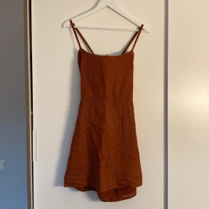 Klänning - Den perfekta sommarklänningen! Jättefin Roströd, kort, flowig bomullsklänning från Nelly i stl 38. Öppen rygg med knytning