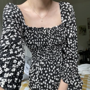 Blommig midiklänning  - Midiklänning med smock och trekvartslånga puffärmar med smock i slutet. Fint skick! 