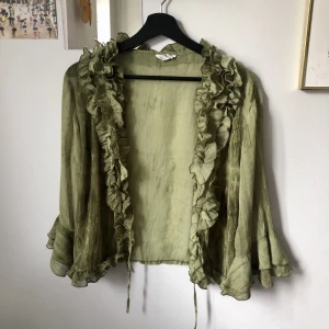 Blus med volanger - Grön blus med volanger. Kan knytas med snören framtill. Storlek M<3