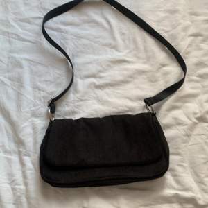 En svart handväska med långt band. Går att förkorta 