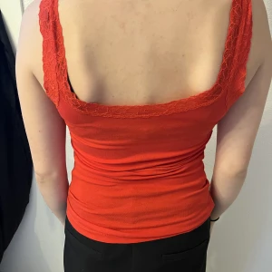 Röd linne  - Söt simpel röt linne med spetts. Inga fel men lapparna är klippta så man kan inte se vilken storlek det är. Sitter som en M eller S