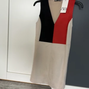 Klänning - Klänning från Zara aldrig använd. Är i mocka material och mix mellan beige/röd/svart. Normal i storlek.