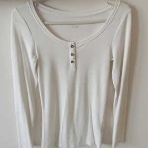 Vit topp/blus/tröja - Långärmad ribbad blus med knappar. Stretchig, så den kommer passa andra storlekar också.