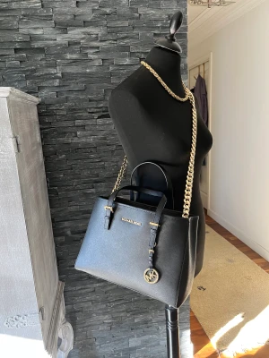 Supersnygg MK  - Toppenfin svart Michael Kors jet set travel handväska/crossbody med gulddetaljer i nyskick mått ca 30x22x13 cm, guldfärgad kedja skickas självklart med. Fler bilder skickas vid intresse. Hämtas på plats eller skickas mot fraktkostnad. 