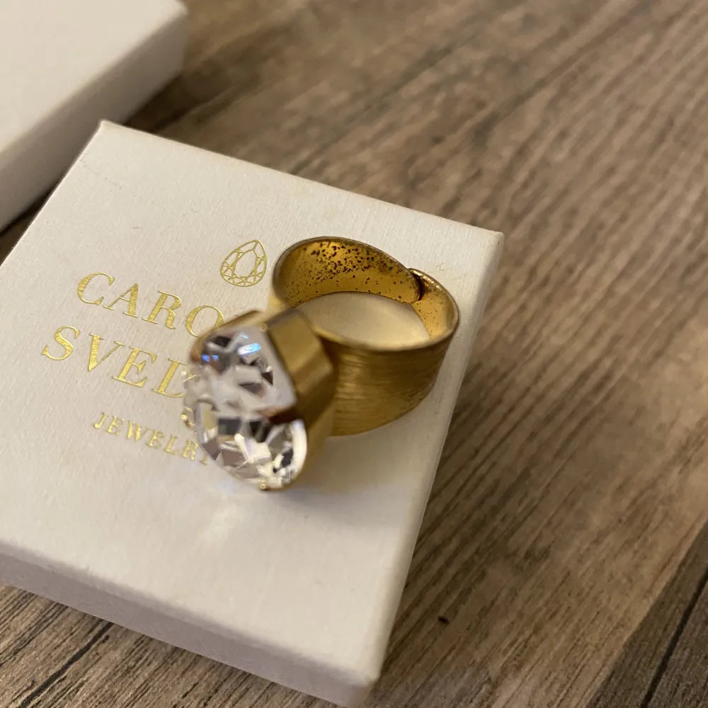 Jätte fin guld ring med klar diamant från Caroline Svedbom. Ringen har lite slitage på insidan men inget som syns när ringen är på. Även piggarna som fäster diamanten är något missfärgade. Ringen är justerbar. Ordinarie pris 595 kr. Asken medföljer🌟. Accessoarer.