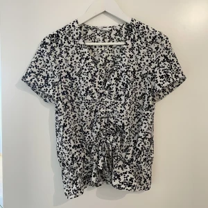 Blommig blus, Cubus (Strl. 36) - Fin blommig blus från Cubus i tunnt material i storlek 36. Den har volanger i nederkant och fin knytdetalj med rosett i fram. I princip helt oanvänd och i superfint skick!