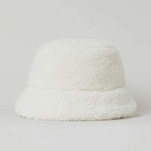 Ny mössa i bucket hat modell i vit pile. Köpt på H&M förra året. Ej använd. Mått: 60cm. Brättets bredd: 6cm. 🤍