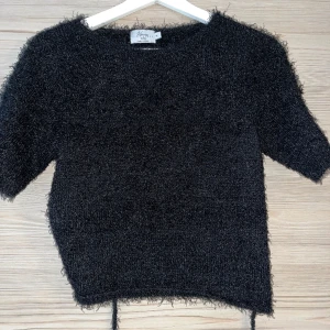 Svart topp med öppen rygg - Svart topp med öppen rygg och knytning nertill (syns på bild 2). Från Hanna Schönbergs kollektion med NA-KD. Inga slitningar elle ränkerna, använd endast ett fåtal gånger.  Kan skicka bild på hur den sitter på mig som är en storlek S vid frågan. 