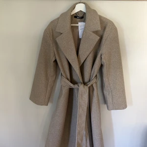 Kappa - En jättefin beige kappa från Ginatricot. Säljer då den inte kommit till användning, är alltså helt oanvänd. Storlek S men passar även vissa M. Köpte för 699kr säljer för 449kr