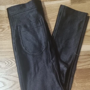 Glansiga byx/leggins  - Ett par snygga glansiga byxor som tyvärr blivit för små. Sparsamt använda och nästintill som nya. Passar både vardag och fest. 
