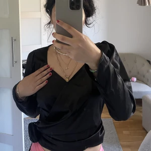 Satinblus NaKd - Säljer en svart satinblus från NA-KD. Det är en omlottblus med puffiga axlar. Endast testad och inga defekter. Väldigt snygg och lätt att justera. 