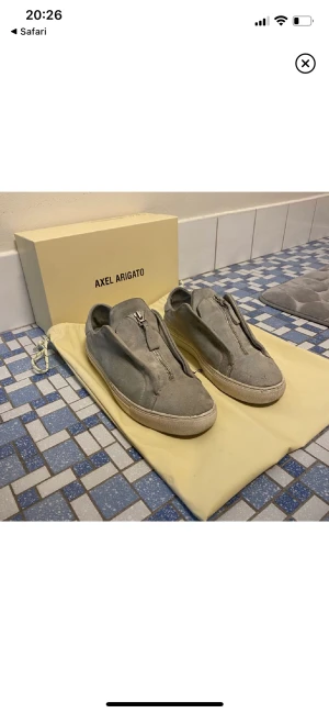 Axel arigato skor  - Ett par clean laceless arigato skor med dragkedja i mitten. Storlek 41