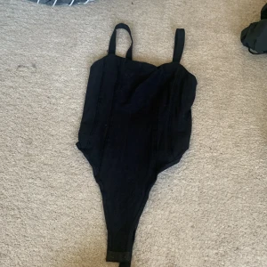Body  - En tight svart body med formgivande mönster. Inga tecken på användning.