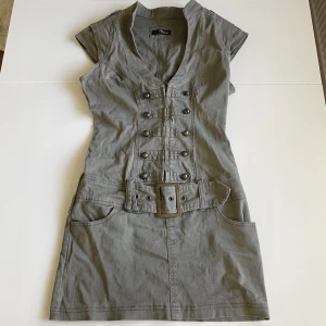 Klänning - Svinsnygg tajt Jane Norman klänning jag endast säljer då den är för liten i bysten och jag kan därav ej få på mig den! Sitter som en smäck med massa snygga detaljer, knappar, dragkedja och bälte framtill⭐️Storlek 10 men uppskattar till en liten S!🤞