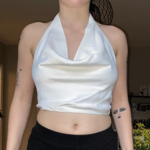 Halterneck topp - Vit halterneck helt ny oanvänd från Zara. Mycket skönt satin tyg av viskos. Draperad halsringning med knytning bak. Storlek M men passar också S!