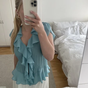 Volangblus - Ljusblå volangblus. Använd fåtal gånger.