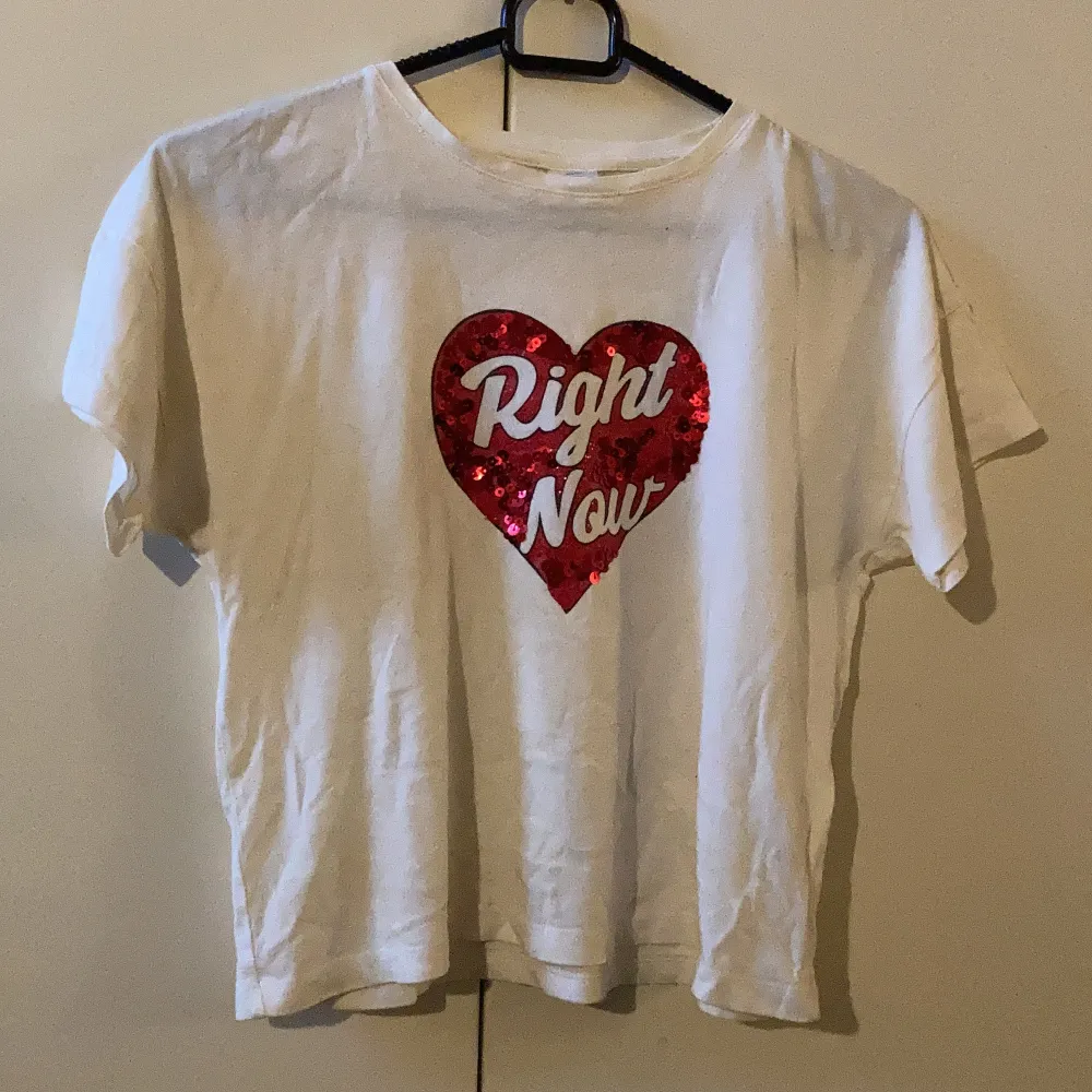 Säljer denna vita t-shirt med ett glittrigt rött hjärta med paljetter där det står ”right now” från Lindex, då den blivit för liten. Använd fåtal gånger, bra skick! ❤️. T-shirts.