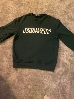 Dsquared2 tjocktröja  - Det är en mörkgrön Dsquared2 tröja som är använd sparsamt. Den är i materialet bomull. Säljer den för att den har blivit för liten. 