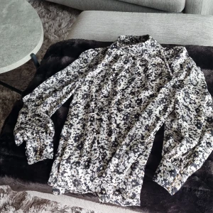 Blus - Blommig blus med små guldknappar på ärmar och bak i nacken.