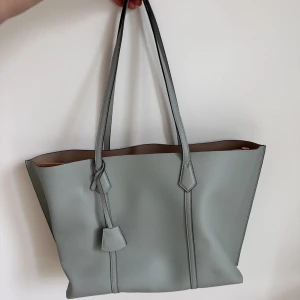 Äkta!! Tory Burch Totebag - Väskan är mycket bra, används sällan. Färg : Seltzer/Pavestone 100% koskinn Nypriss : 5545kr  vänligen chatta mig för fler bilder. Vi kan diskutera för pris också.