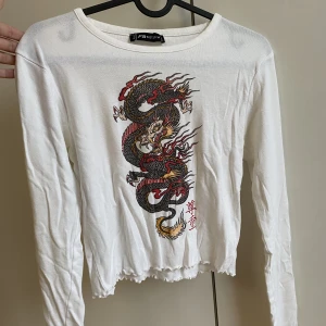 Långärmad tröja  - En långärmad tröja med ett draktryck på framsidan. Använd men i fint skick!