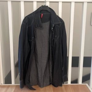 Mörkgrå jeansskjorta  - En mörkgrå/mörkblå jeansskjorta som aldrig blivit använd. Ser lite ut som en oversized skjorta på en M/L person. 