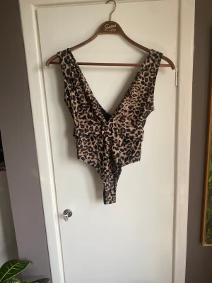 Högtskuren baddräkt med öppen rygg - Leo print och ett snyggt bälte Högt vid höfterna och djup urringning både fram och vid ryggen