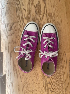 Lila Converse strl 37 - Ett par lila, låga Converse i storlek 37.