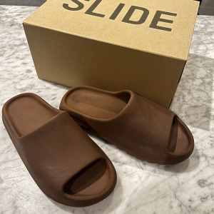 YEEZY slide , Flax - Säljer nu mina YEEZY slides, flax i storlek 46, då dem inte passar mig längre. Skorna passar för någon med storlek 42-44.  Skorna är köpta på ADIDAS CONFIRMED appen sommaren 2022.  Skick: 7/10 PRIS: 800kr 