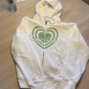 Vit dragkedja hoodie med grönt tryck som det står ”HappyHills”  Size:Small Använd 1 gång.