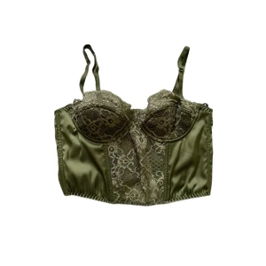 Grön korsetttopp - Söt croppad korsett top från Urban Outfitters. Säljer pga för små kupor så har inte använt den. Skulle passa någon med ca a-b kupa kanske c. Storlek M men sitter som en S. Köptes för ca 400kr.