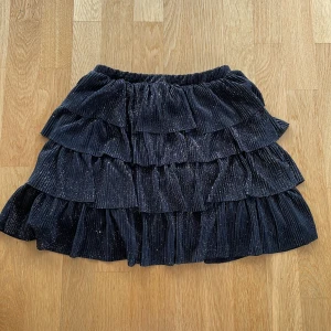 Glittrig volangkjol  - Glittrig svart volangkjol från Zara Kids, passar som storlek XS. Köpt här på Plick men endast använd ytterst få gånger. Skriv för fler bilder