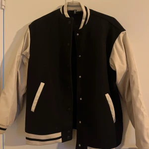 Baseball Jacket Oversized  - En oversized baseball jacka med ärmar av skinnimitation. Brukar bära storlek S i vanliga fall men denna är i XXS och fortfarande stor. Bara använd ett fåtal gånger 