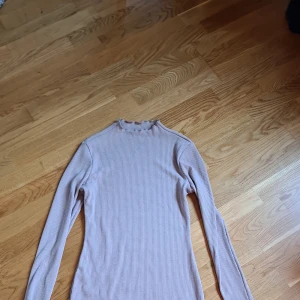 Långärmad stickad klänning  - Långärmad stickad klänning i skönt material. Aldrig använd endast provad. Det är strl M men jag tyckte den blev för kort på mig. Färg beige/grå