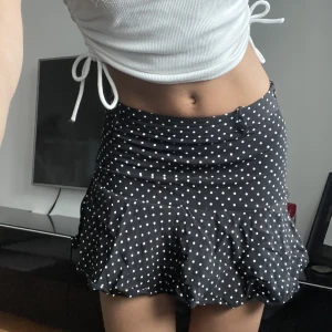 Kjol - Kjol med inbyggda shorts, tillkommer band som man kan knyta som bälte. Går att ha lågmidjat och högmidjade. ”Mini-kjol”