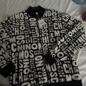 Moschino zip-tröja - Helt ny oanvänd äkta moschino tröja, kvitto finns. Inköpt från thernlunds. Fick den i present men tyckte inte den passade mig. Nypris 2499:-